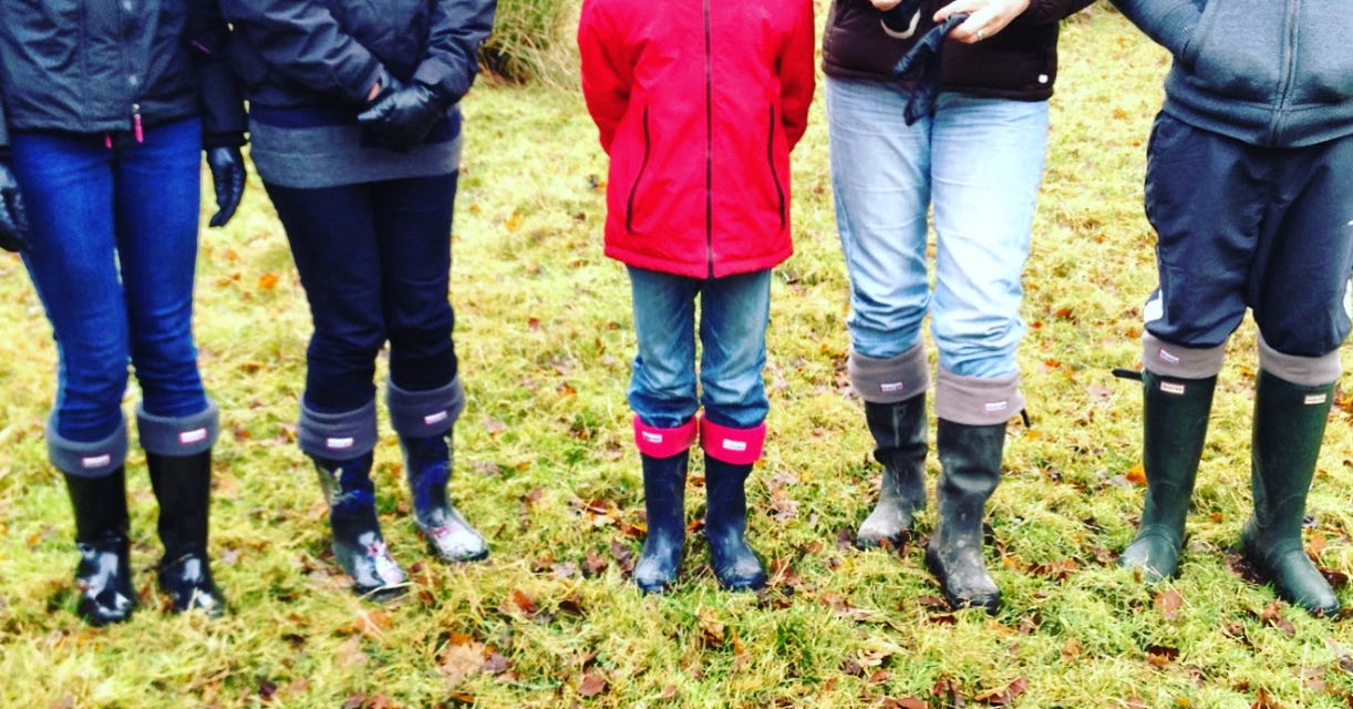A row of people from the waist down in winter welly boots