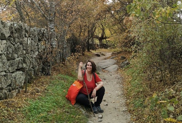 Photo of myself sitting on the grass by a trail in the woods.