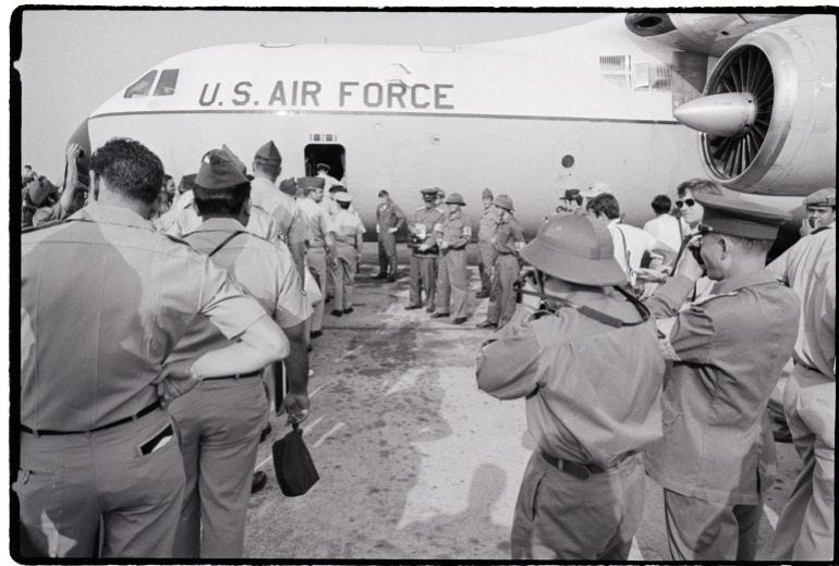 American troops board a US Air Force jet during a test withdrawal at Tan Son Nhut Air Base while Vietcong and North Vietnamese officers take photographs near Saigon, Vietnam American troops board a US Air Force jet during a test withdrawal at Tan Son Nhut Air Base while Vietcong and North Vietnamese officers take photographs near Saigon, Vietnam