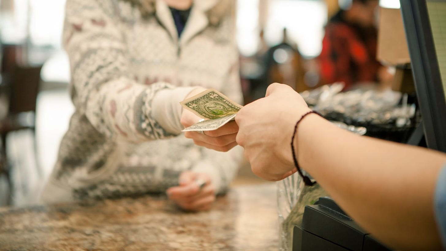 Female customer handing payment to waiter over counter - stock photo