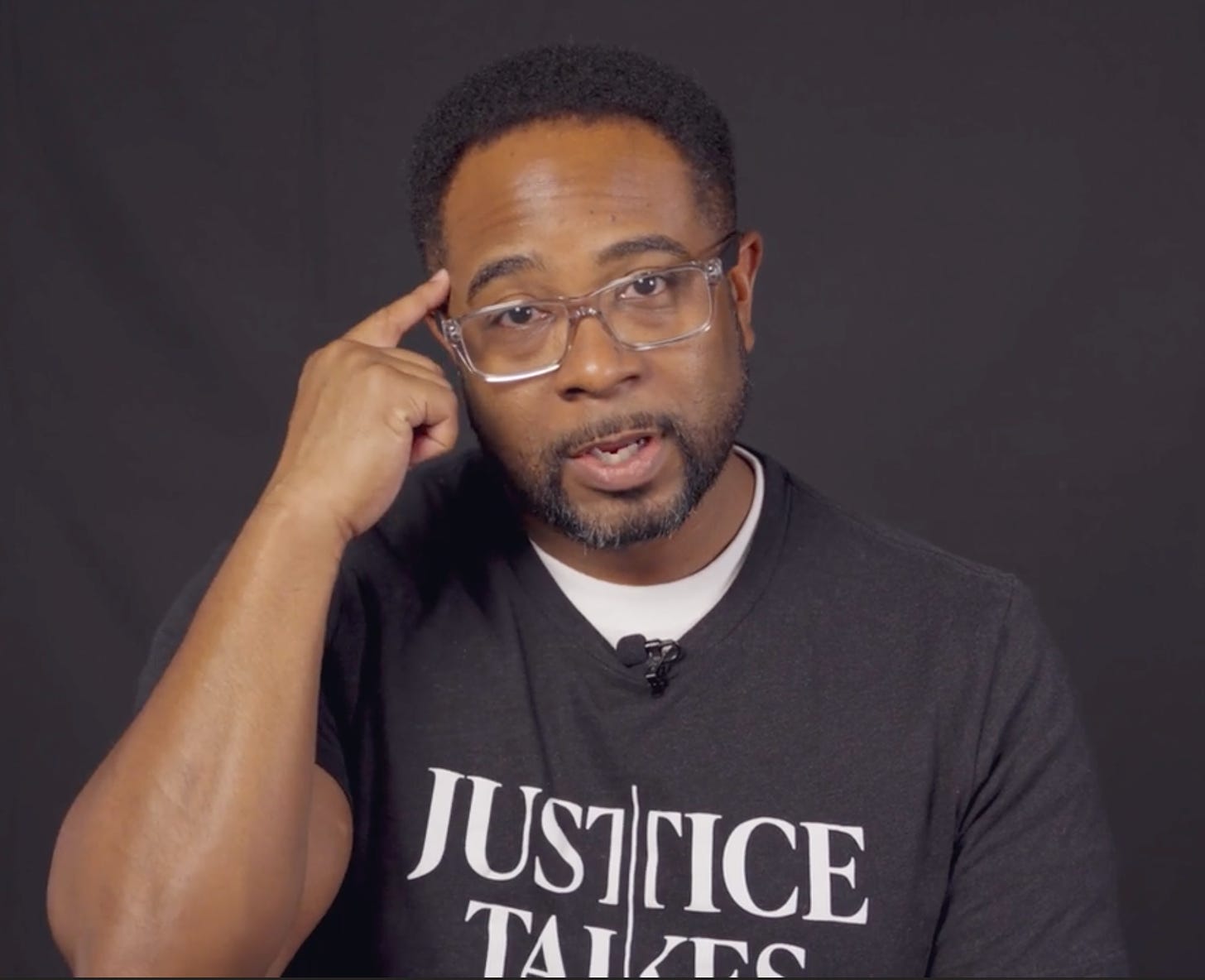 Jemar Tisby in Justice Takes Sides t-shirt in front of black background