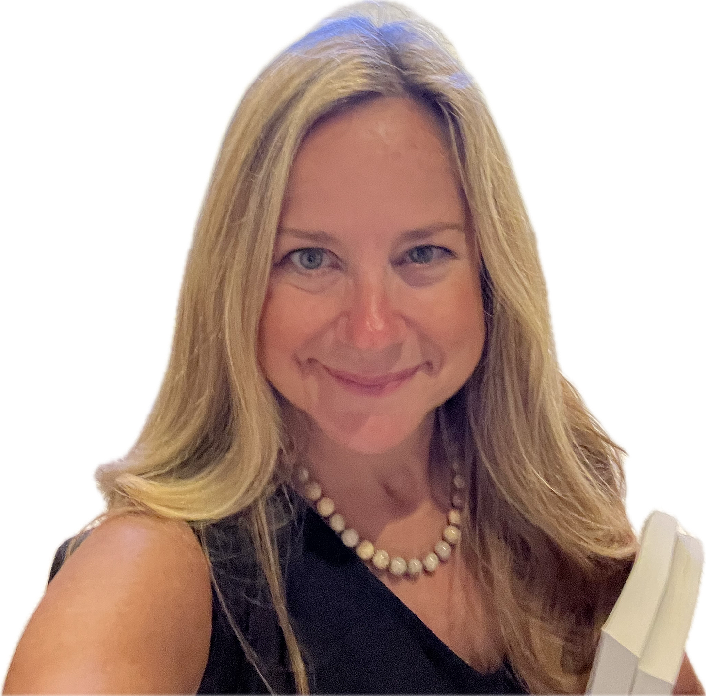 Blonde woman with shoulder length hair holds books and looks at camera. She wears pearls and a black shirt. 