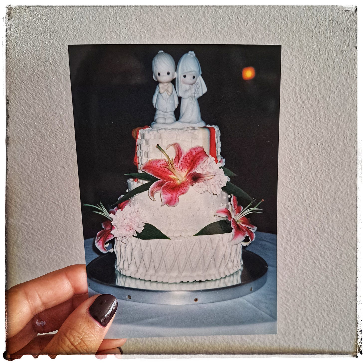 Tarta de novios de tres pisos adornada con flores y en la parte superior figura de novio y novia. Foto de archivo familiar. 