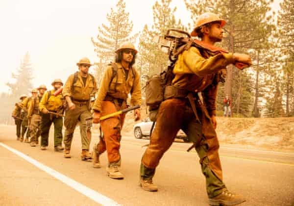 A firefighting crew walks in a file with equipment in their hands. A firefighting crew walks in a file with equipment in their hands.