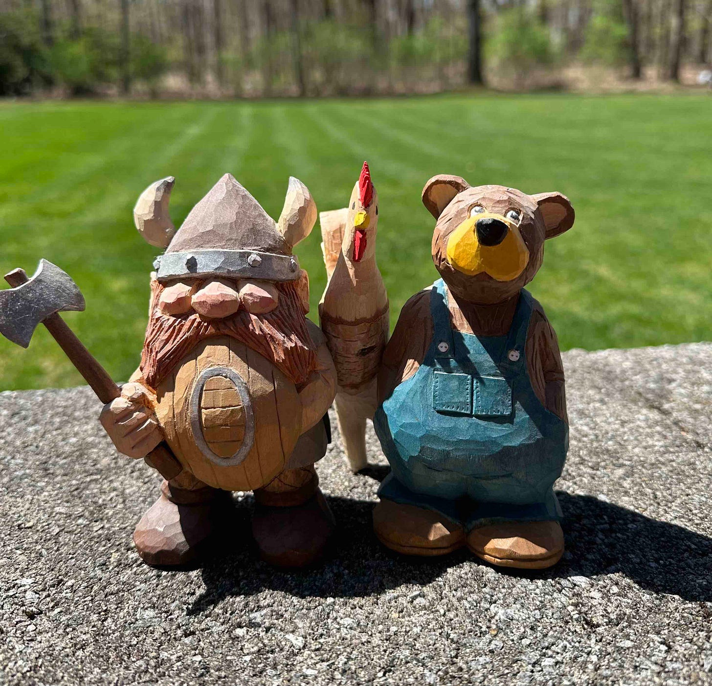 photo of three carved figures: viking, rooster, and bear