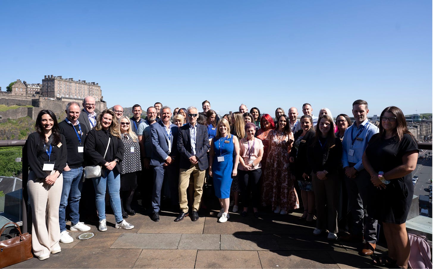 The photo is of the attendees of the Scottish Financial Enterprise Summit standing outside with a view of a blue sky in the background