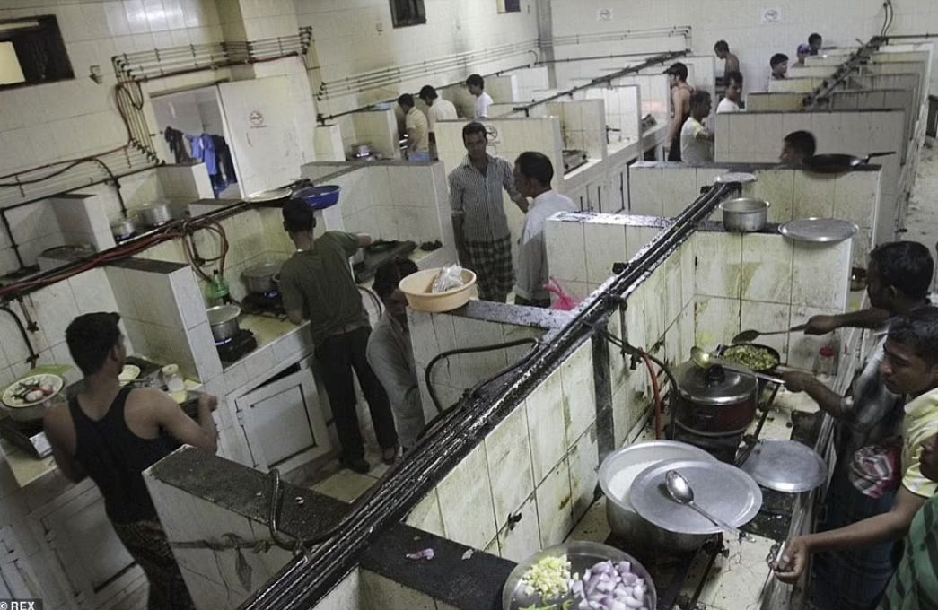 Foto de cozinhas e espaços para alimentação de trabalhadores em Sonapur, diversos cubículos separados por paredes baixas, muito sujos, com fogões, panelas e armários.