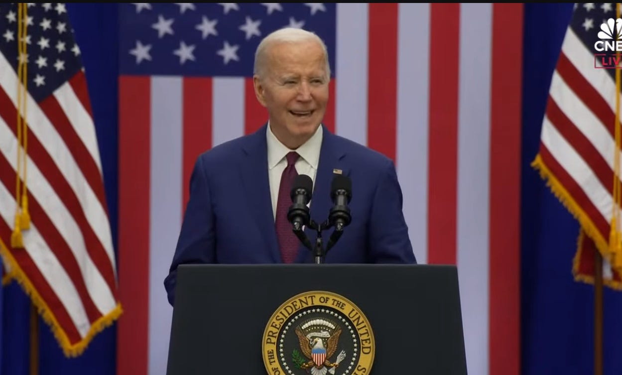 Joe Biden gives a speech at a podium with the presidential seal, in front of a big US flag
