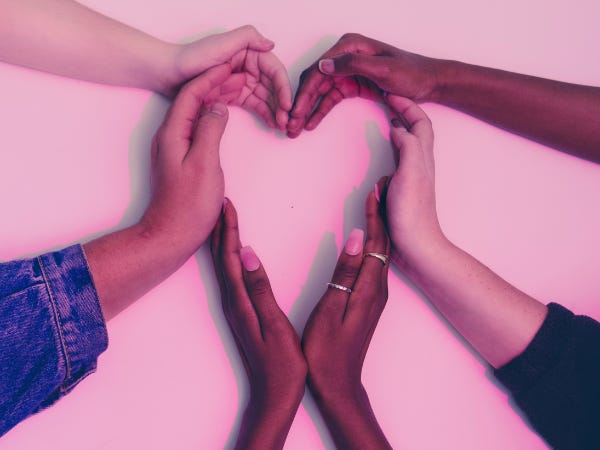 Hands of various diverse women forming a heart 