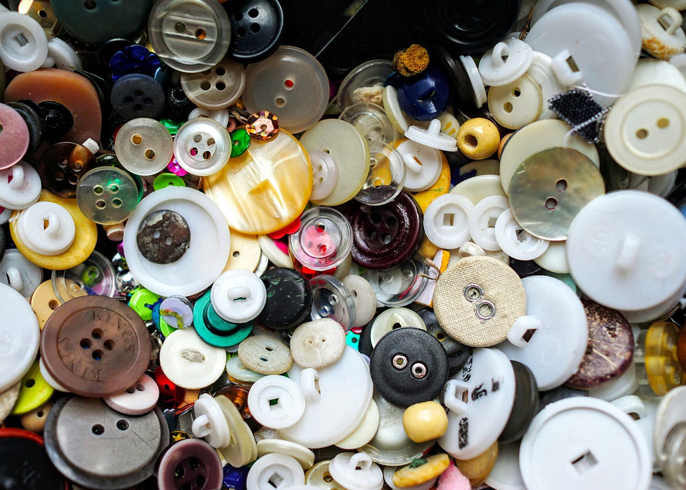 A close up of a great number of clothing buttons, various shapes and colours