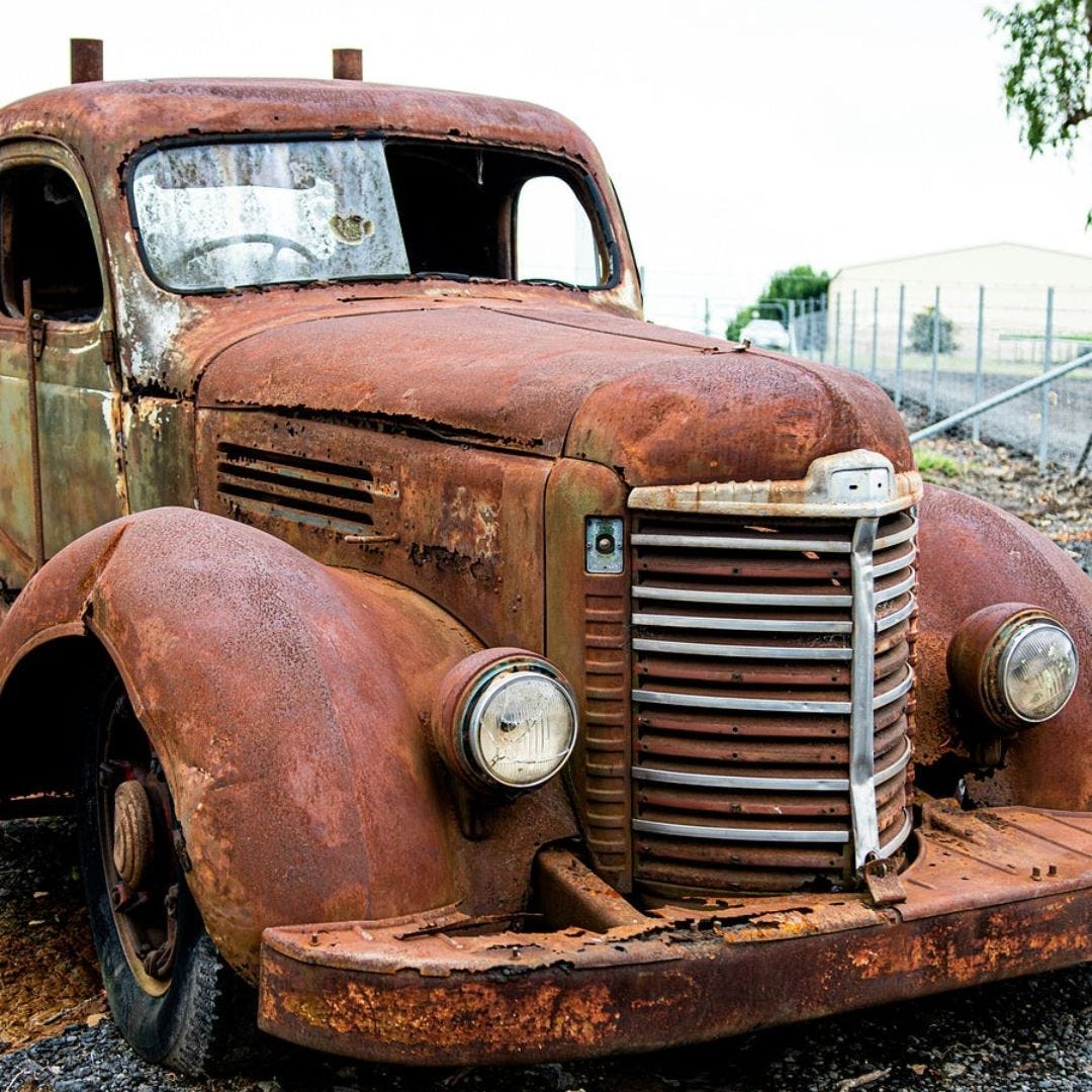 A very rusty pick up truck with intersting grill design