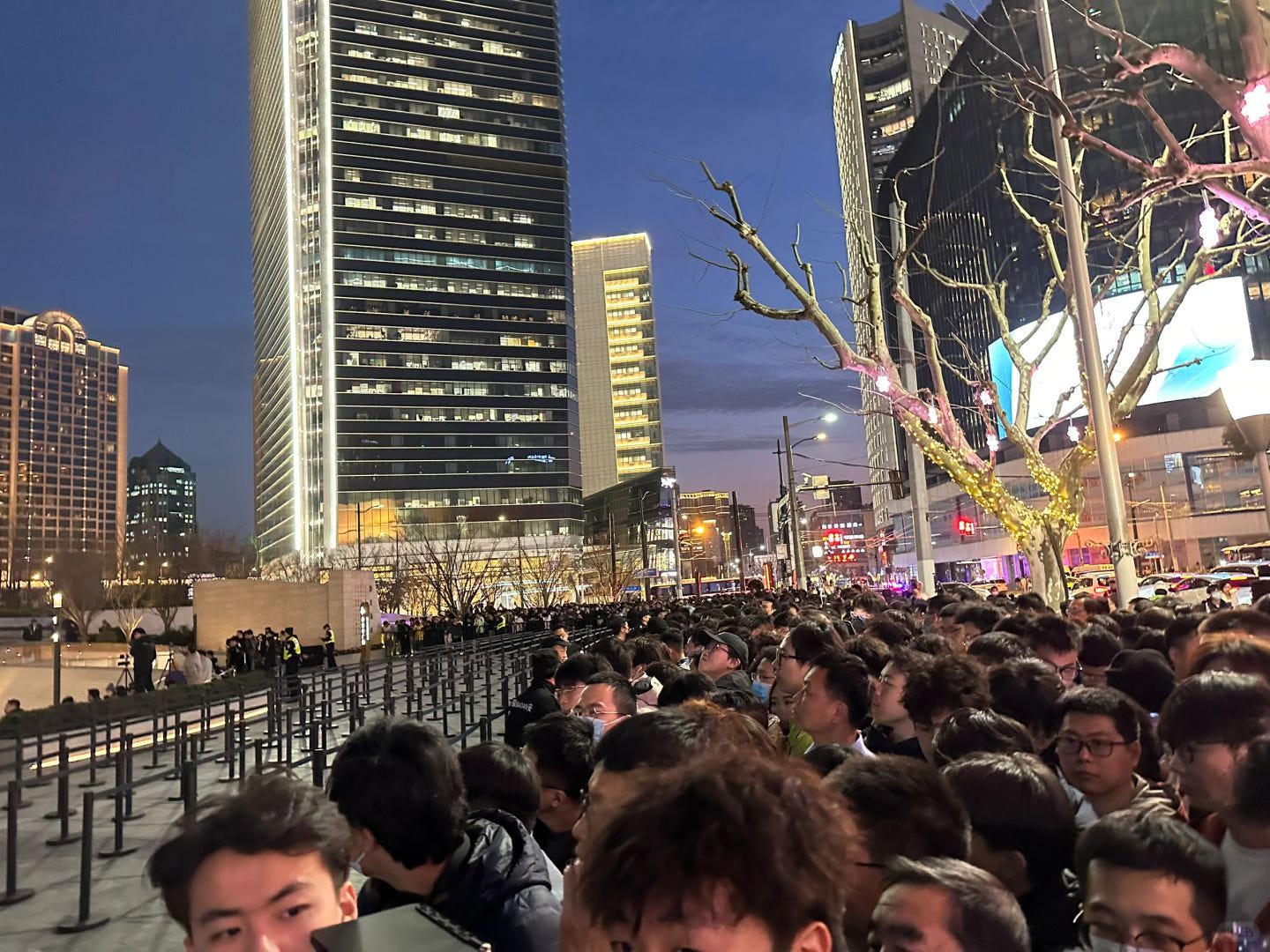 A view from the line at Apple Jing'an. A crowd is packed along the roadside.
