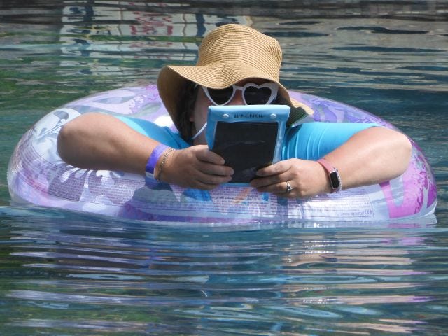 Amy reading in a floatie, in a pool