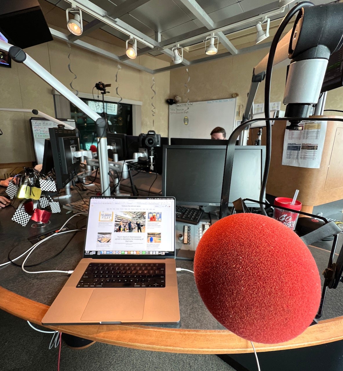 The first-person view from my seat at the radio station with my laptop on a desk and the microphone in front of me at The Fan.