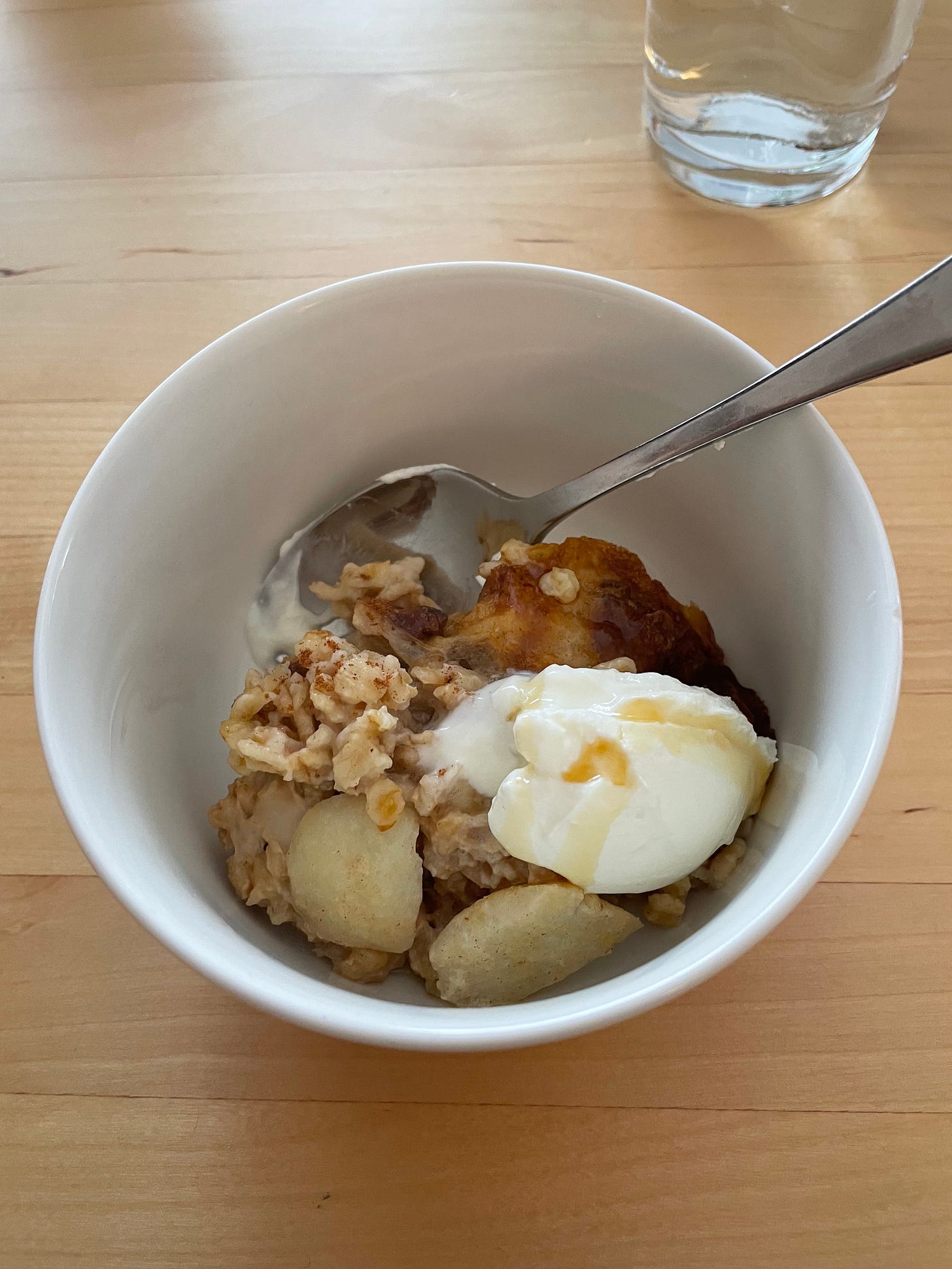 Bowl with baked apple porridge, served with extra cinnamon and yoghurt.
