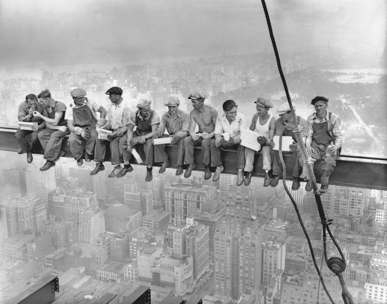 Eleven men sitting on a steel beam high over a skyscraper.