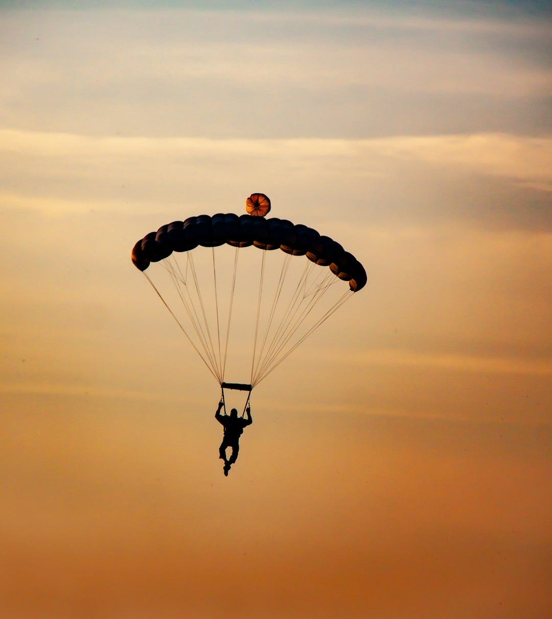 person in parachute under white clouds during daytime person in parachute under white clouds during daytime