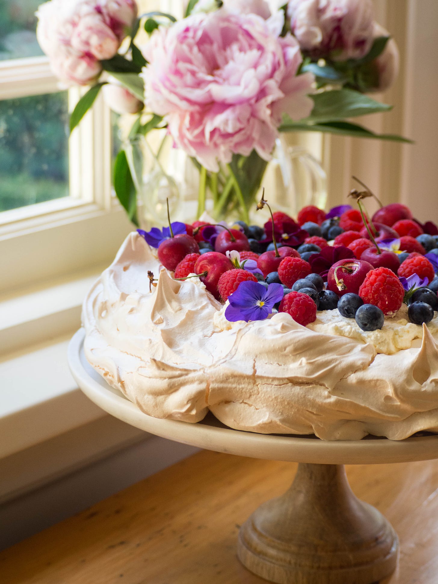 Pavlova with Berries and Cherries Pink Peonies in Background