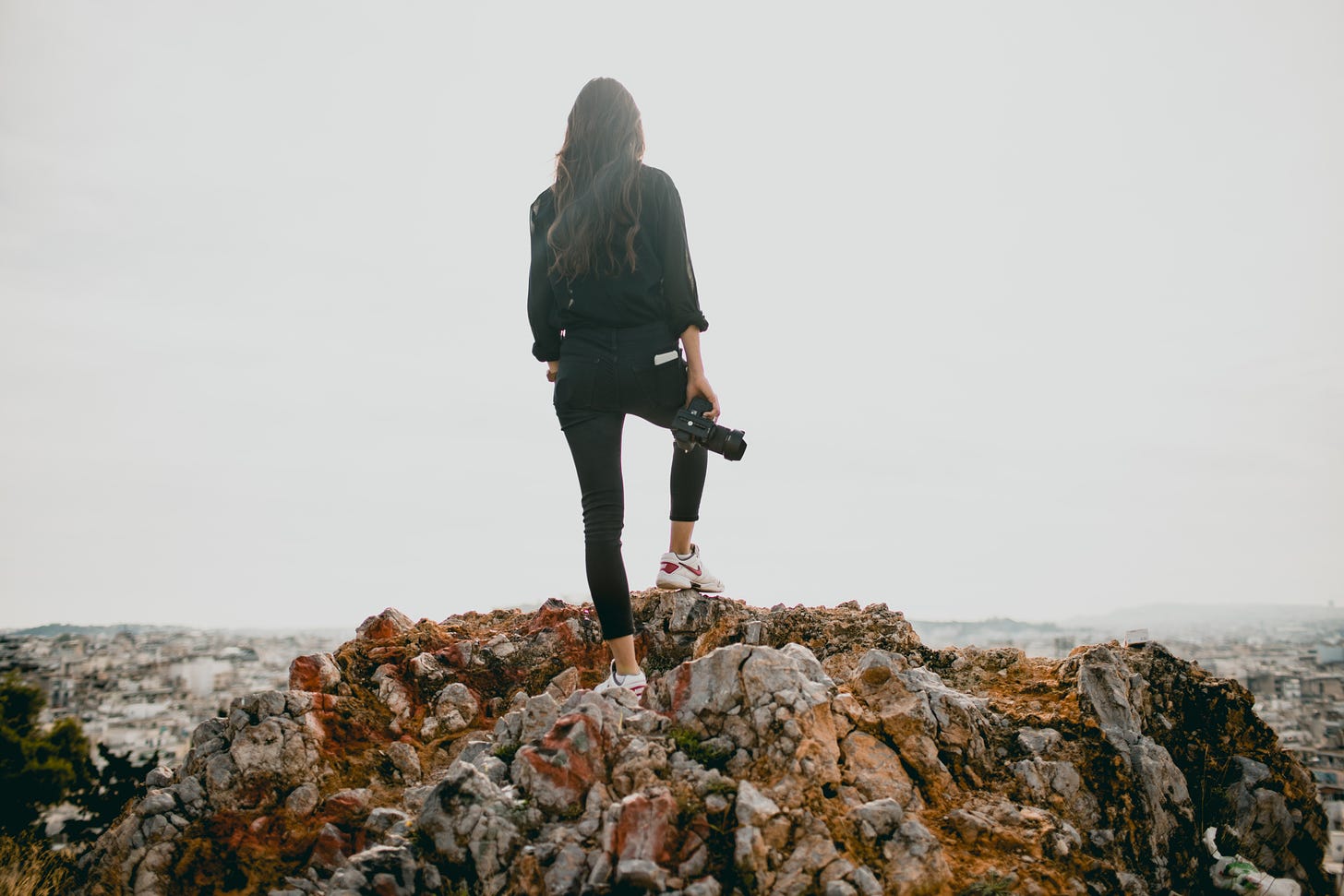 Photo by Rachel Martin on Unsplash of female influencer standing on rocks looking off into the horizon