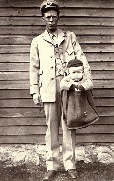 File:Uniformed Letter Carrier with Child in Mailbag.jpg