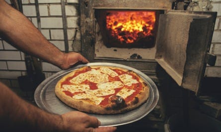 hands on pizza next to oven