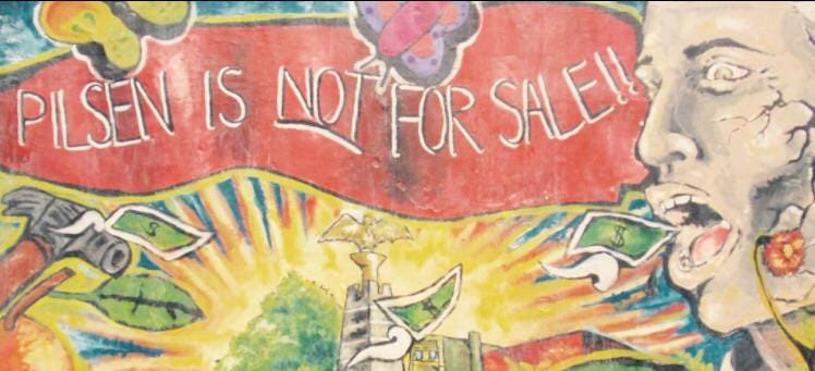 A brightly colored mural with the words "Pilsen is Not For Sale" with a hammer, a face, and an eagle statue are surrounded by dollar bills.