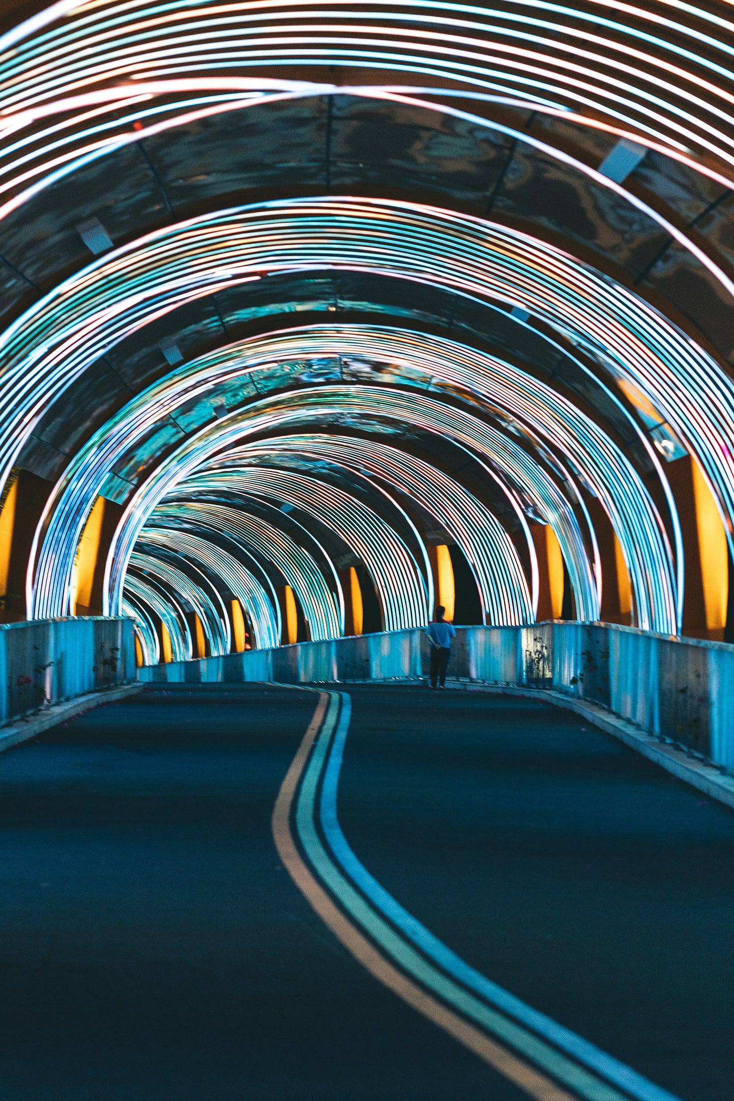 A road tunnel brightly lit with rainbow colored neon lights