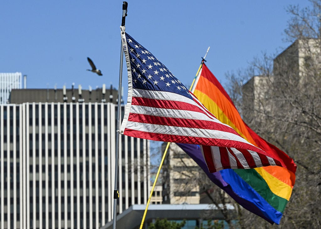 U.S. and Pride rainbow flags on display on a sunny day.