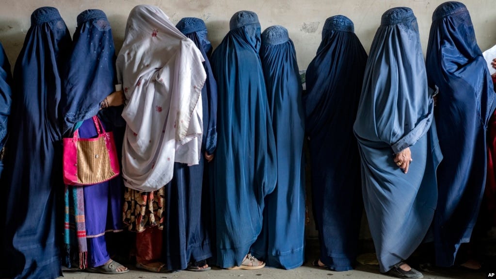 FILE - Afghan women wait to receive food rations distributed by a humanitarian aid group, in Kabul, Afghanistan, May 23, 2023. The Taliban have arrested women for the first time in Kabul for wearing "bad hijab." 