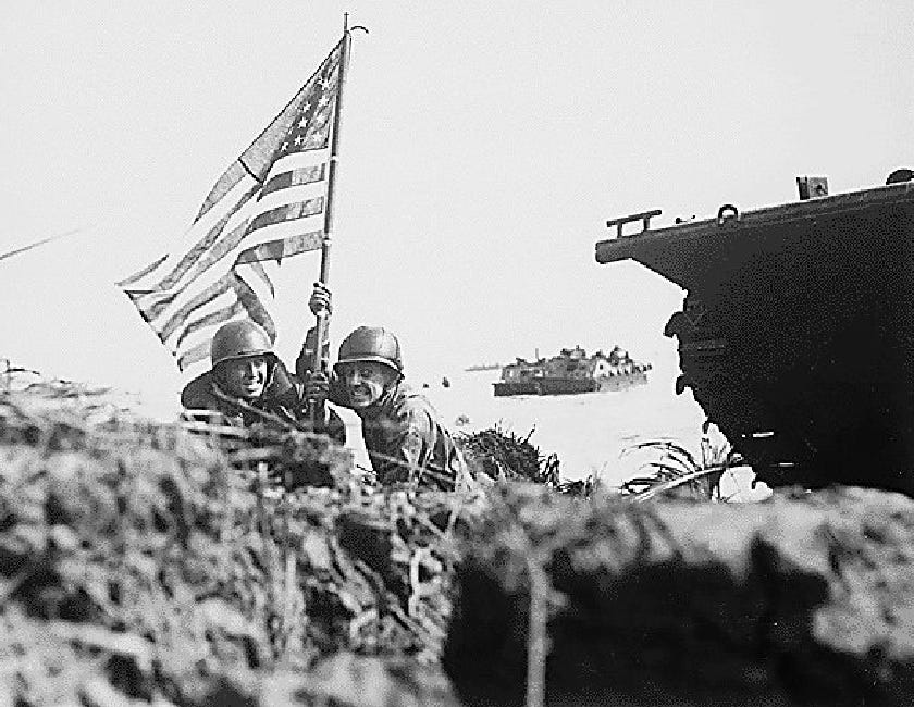 Black and white photo depicting two soldiers gripping the first American flag hoisted at Guam.