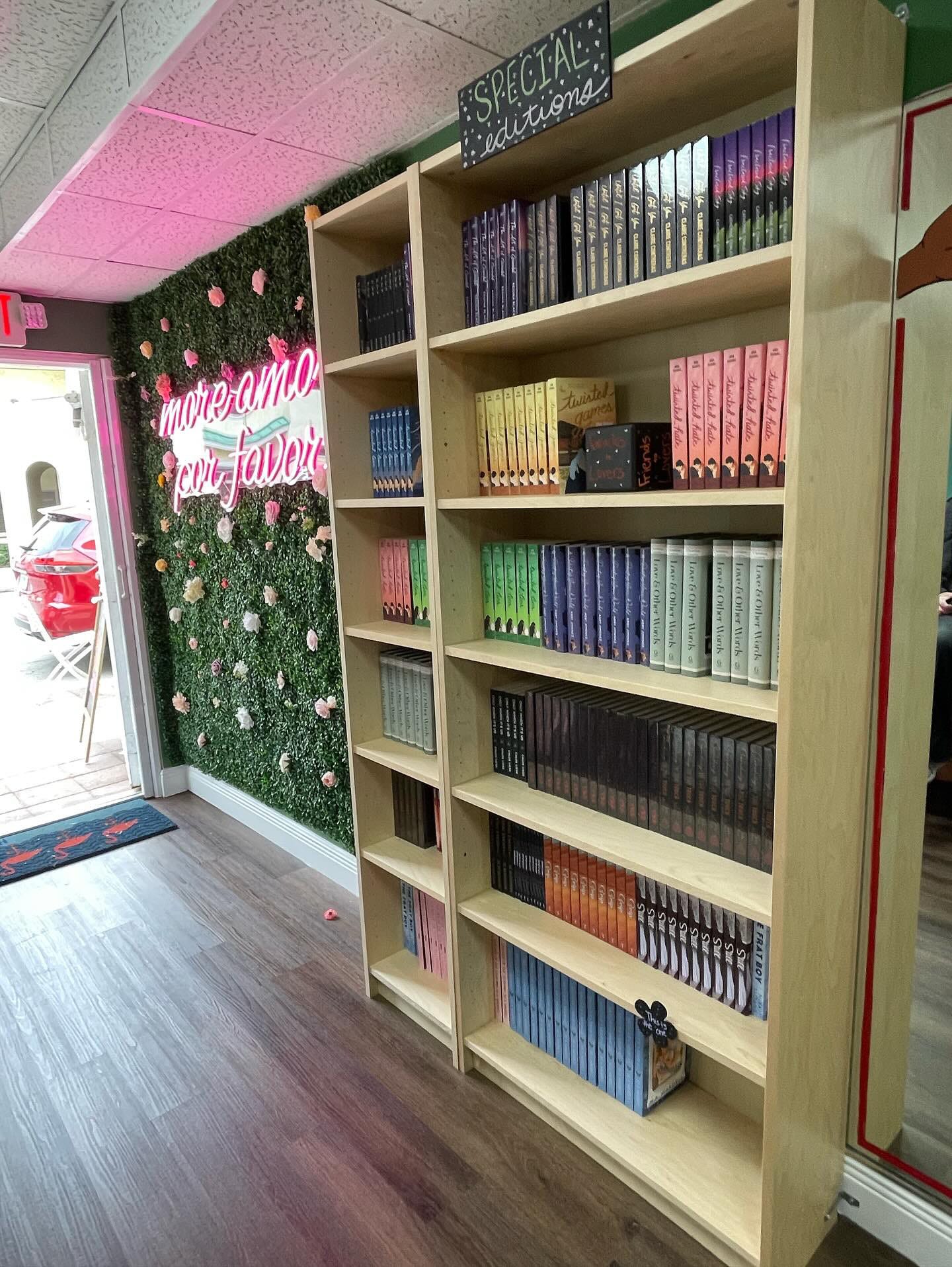 A picture of Steamy Lit Bookstore that shows a shelf of special editions and then the wall art that says "more amor por favor"