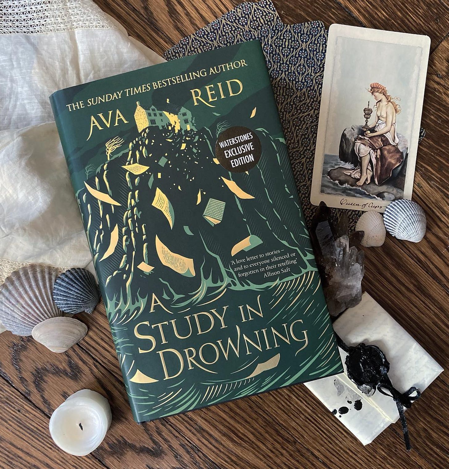 a flat lay of A Study in Drowning with tarot cards, seashells, crystals and a vintage handerkerchief