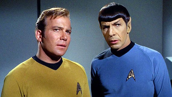 TOS Kirk and Spock look just off camera at something perplexing. Maybe they just found the fan fiction Bones was writing.