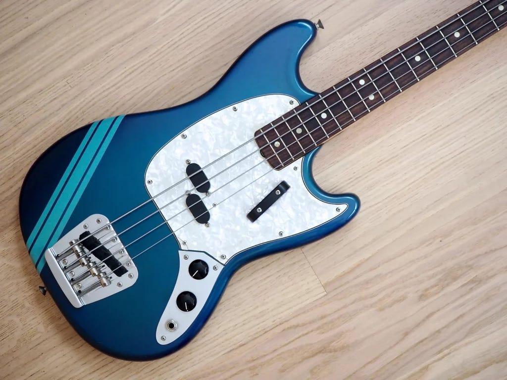 1970 Fender Mustang Competition Bass in Lake Placid BLue laid on the hardwood floor.
