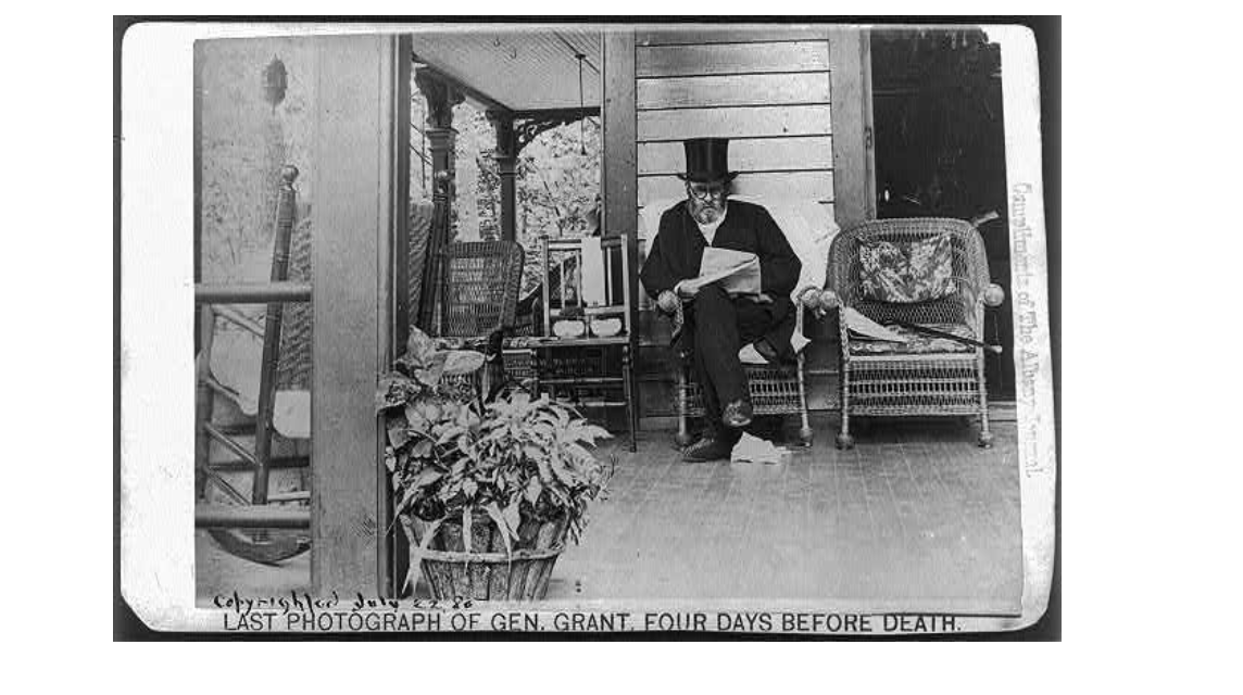 Black and White picture of President Grant sitting on a porch with a top hat reading a paper