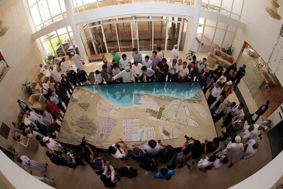 Chinese investors listening to an explanation as they check the model of the dry dock which is to be... [+] built following an economic agreement in the Omani port city of Duqm. (MOHAMMED MAHJOUB/AFP/Getty Images)