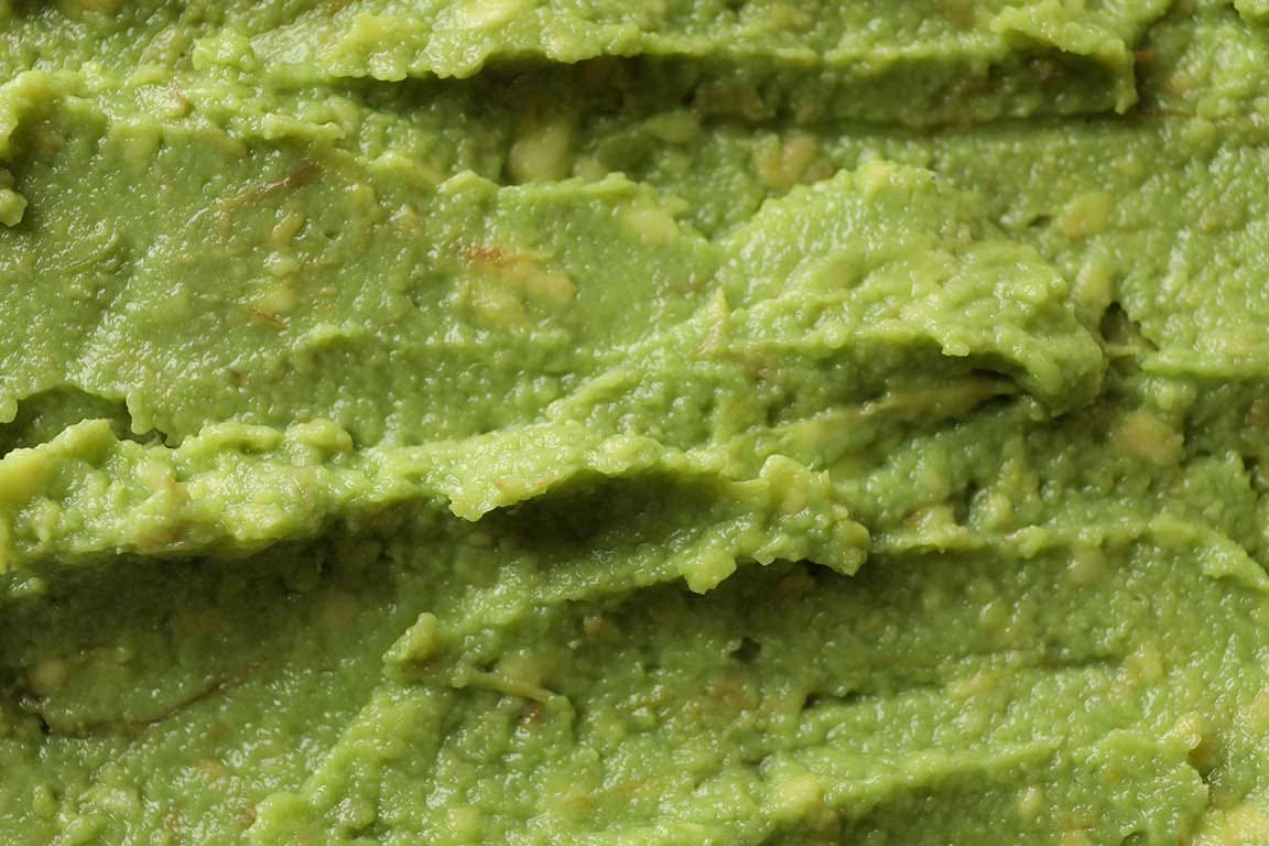 Extreme closeup of a schmear of guacamole cropped in a rectangle