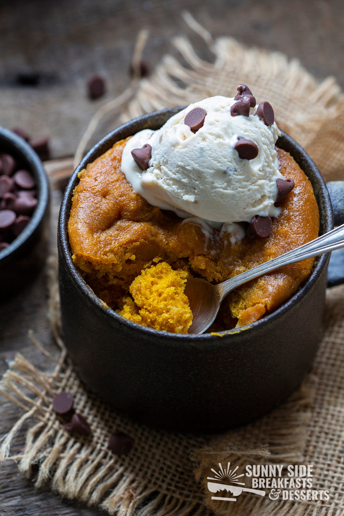 Pumpkin cake in a mug topped with vanilla ice cream.