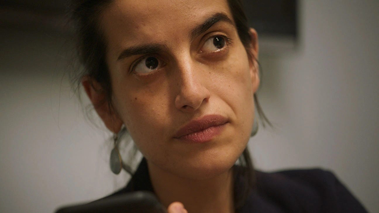 A still from A Still Small Voice. A close-up of a woman holding up her cell phone and looking offscreen to the right.