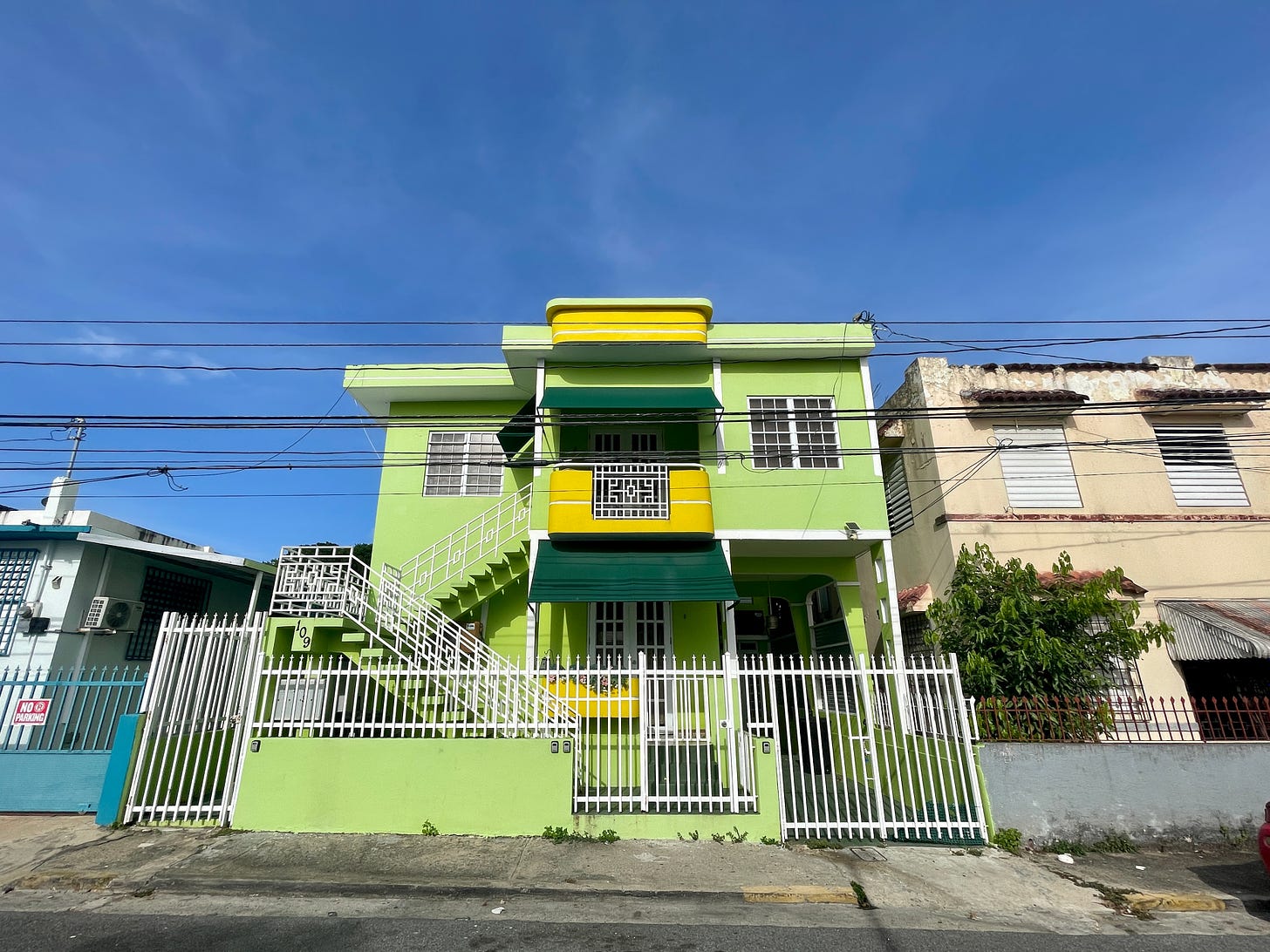 A colorful, lime green and yellow house in San Juan, blue sky in the background.
