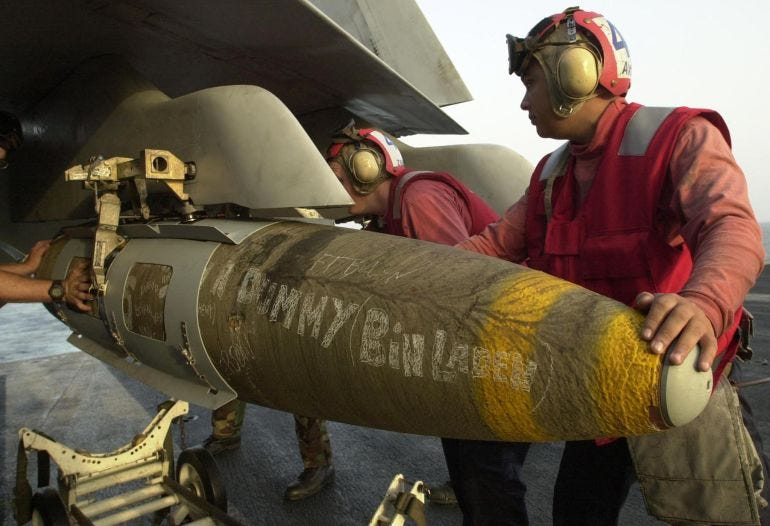 A 2,000 pound GBU-16 bomb is unloaded onto a US Navy F/A-18 Hornet parked 03 Novembeer 2001 on the aircraft carrier USS Theodore Roosevelt by unidentified Avionics Ordenance personnel. The Lasar guided bomb is typical of what pilots are dropping on Afghanistan, the military operations are being conducted from the USS Theodore Roosevelt which is afloat somewhere in the Arabian Sea with operation Enduring Freedom. AFP PHOTO/Mannie Garcia (Photo by MANNIE GARCIA / GANNETT/ARMY TIMES PUBLISHING CO / AFP)