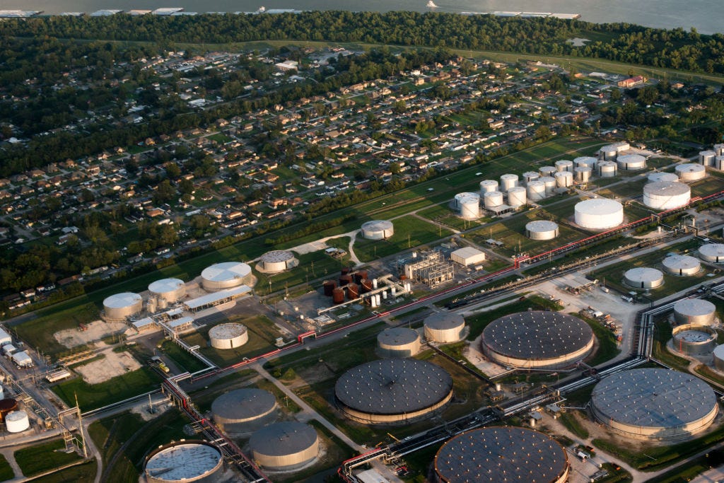 Aerial view of refineries and storage tanks adjacent to a neighborhood of houses