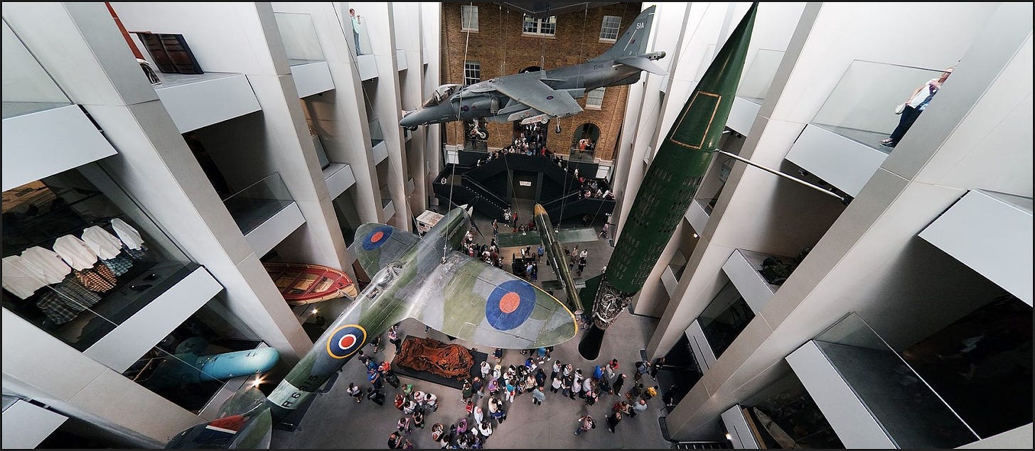 Wide-angle, high-level view of IWM London's atrium, looking down on the suspended Spitfire and other exhibits.