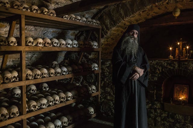 r/europe - a person standing in front of a stack of skulls