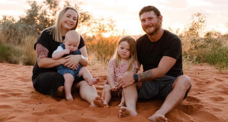 Millicent Edwards with her dad Cody and mum Amanda who is holding her one-year-old brother in the outback.