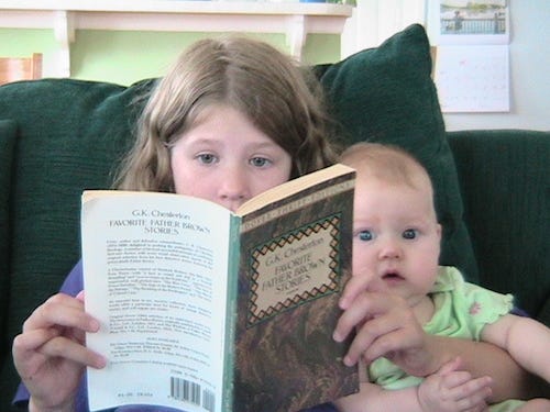 Summer 2006: Jane, age 11, reads a book of Father Brown stories while cuddling baby Rilla.