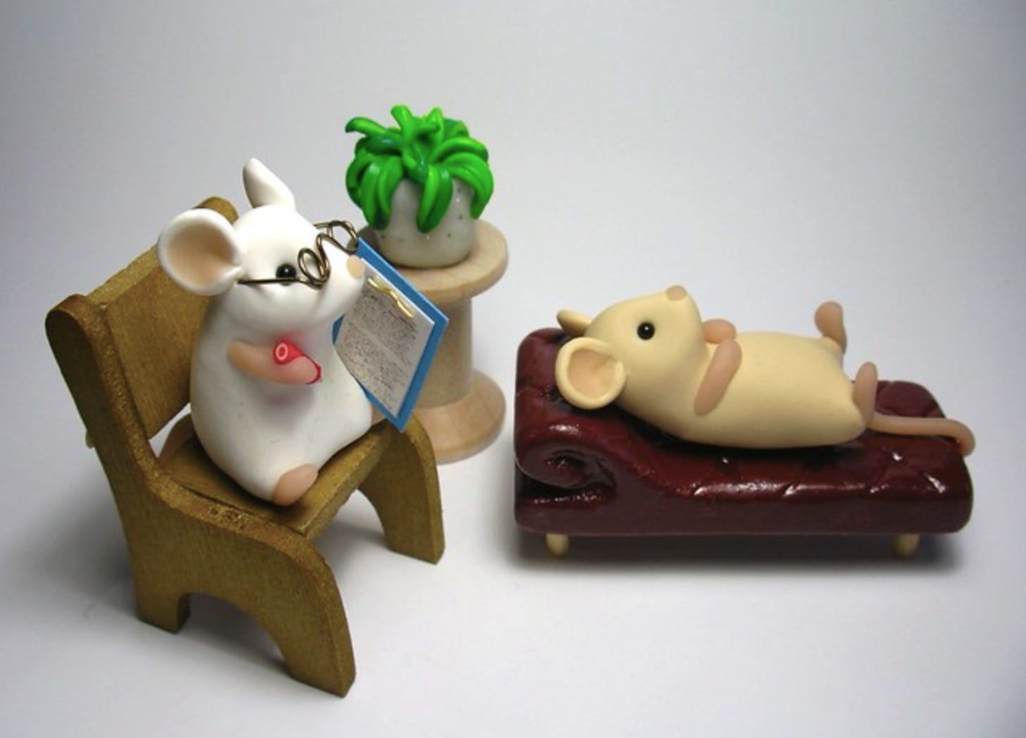 Image of a mouse therapist wearing glasses and holding a notepad and a mouse patient lying on a couch. They are made of clay.