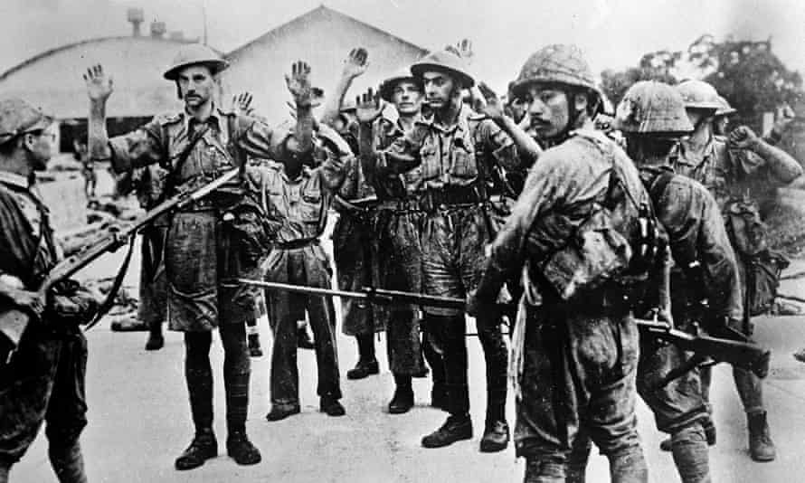 Black and white photo of British soldiers surrendering to Japanese soldiers during World War II. The photo depicts several British soldiers with their hands up to several Japanese soldiers with bayonetted rifles. Singapore fell to the Japanese in February 1942.