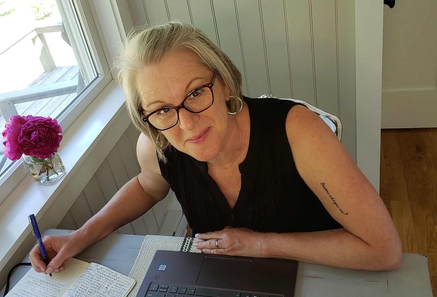 woman writing in journal next to peonies