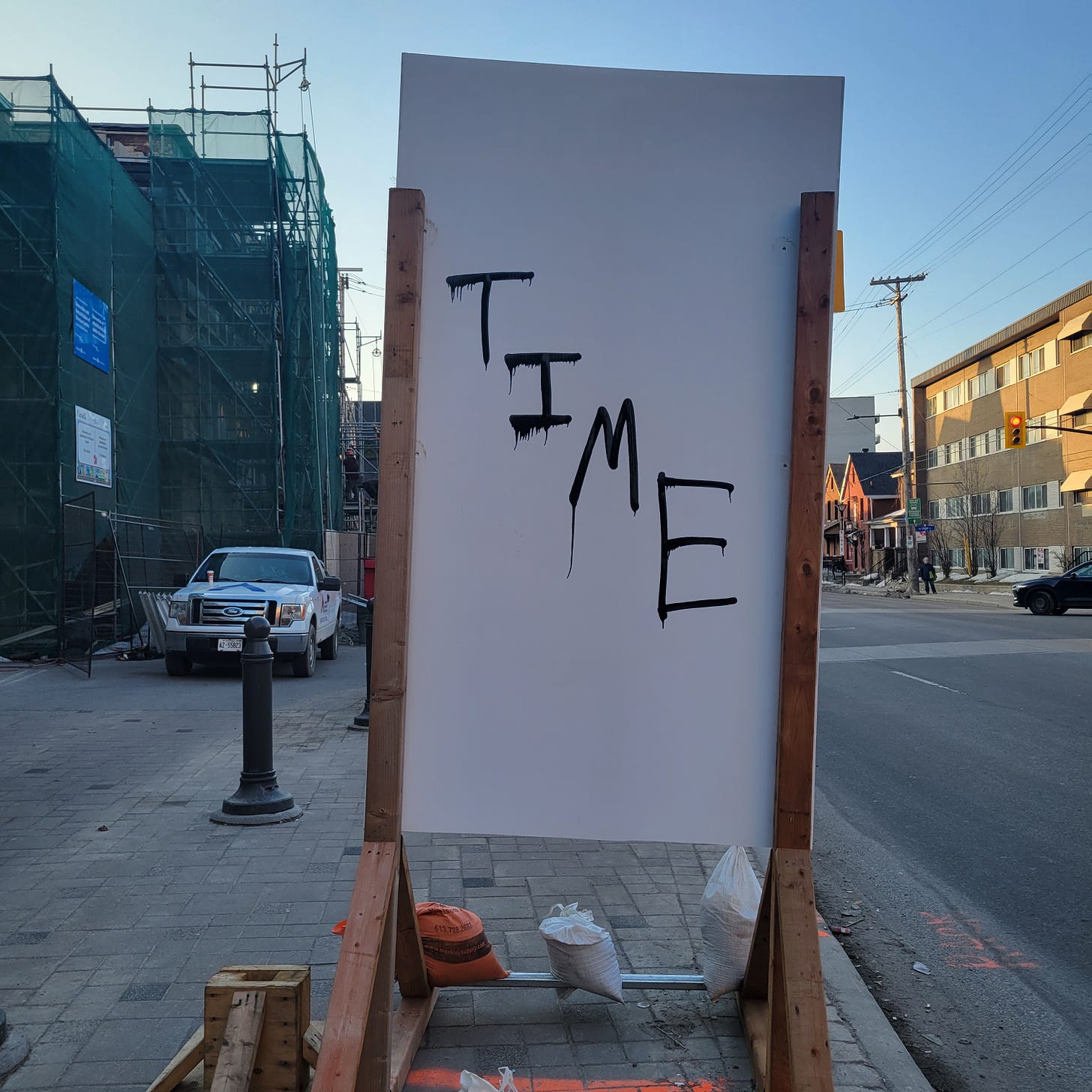 back of construction sign on Bronson in Centretown West-ish, the word "Time" painted diagonally downwards in black